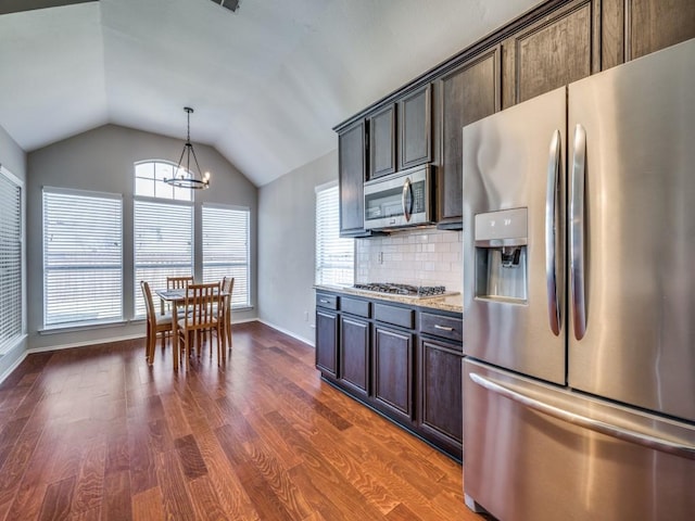 kitchen featuring dark wood finished floors, lofted ceiling, an inviting chandelier, stainless steel appliances, and backsplash