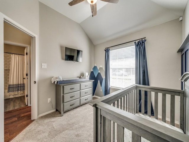 bedroom with lofted ceiling, ceiling fan, light colored carpet, baseboards, and a nursery area