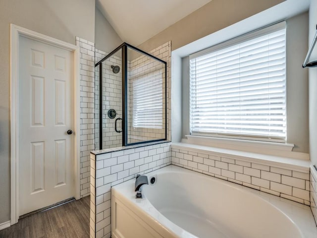 full bath featuring lofted ceiling, wood finished floors, a shower stall, and a bath