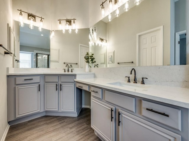 full bathroom with wood finished floors, a shower with door, a sink, and double vanity