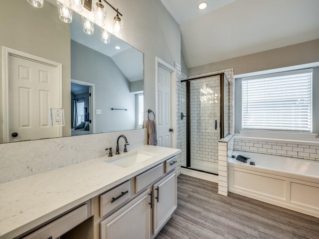 bathroom featuring a garden tub, lofted ceiling, a stall shower, vanity, and wood finished floors