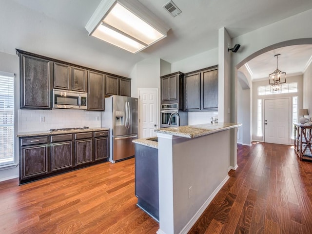 kitchen with stainless steel appliances, plenty of natural light, a peninsula, and dark brown cabinetry