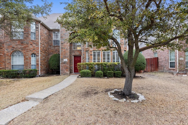 view of front facade featuring brick siding and fence