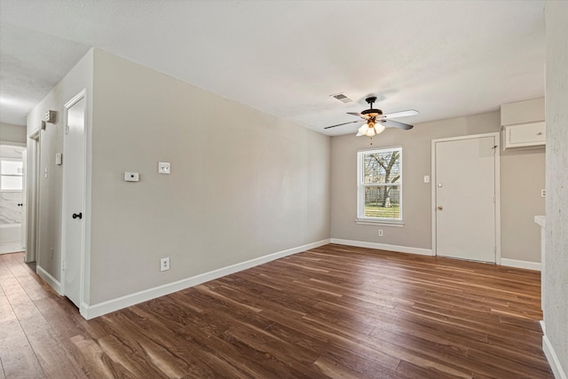 spare room featuring a ceiling fan, visible vents, baseboards, and wood finished floors