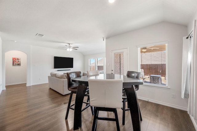 dining area featuring arched walkways, visible vents, ceiling fan, vaulted ceiling, and wood finished floors