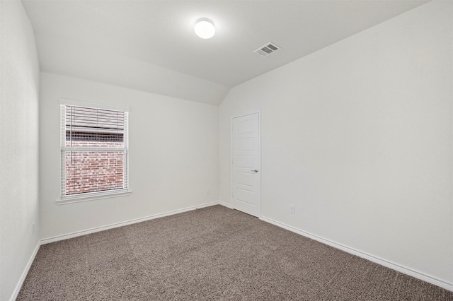 unfurnished room with lofted ceiling, dark colored carpet, visible vents, and baseboards