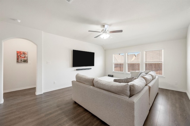 living room featuring arched walkways, dark wood-style flooring, ceiling fan, and baseboards