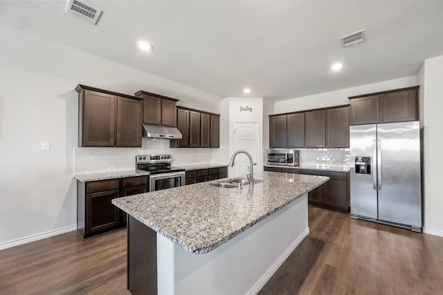 kitchen with dark brown cabinetry, dark wood finished floors, stainless steel appliances, under cabinet range hood, and a sink