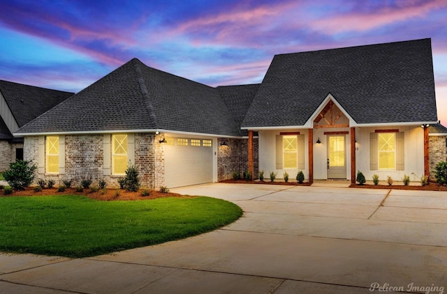 view of front of home with a garage, a shingled roof, concrete driveway, a front lawn, and brick siding