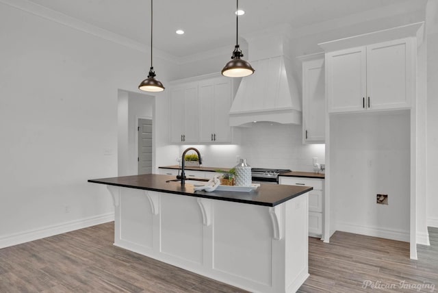 kitchen with white cabinets, dark countertops, a sink, stainless steel gas stove, and light wood-type flooring