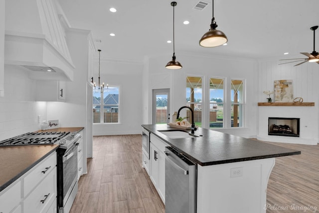 kitchen with crown molding, dark countertops, premium range hood, a sink, and stainless steel appliances