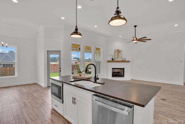 kitchen featuring stainless steel appliances, dark countertops, a wealth of natural light, and a sink