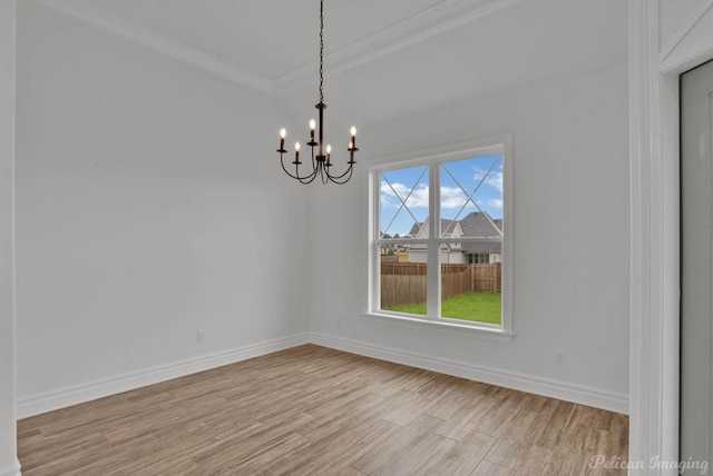 unfurnished dining area featuring crown molding, baseboards, an inviting chandelier, and light wood-style flooring