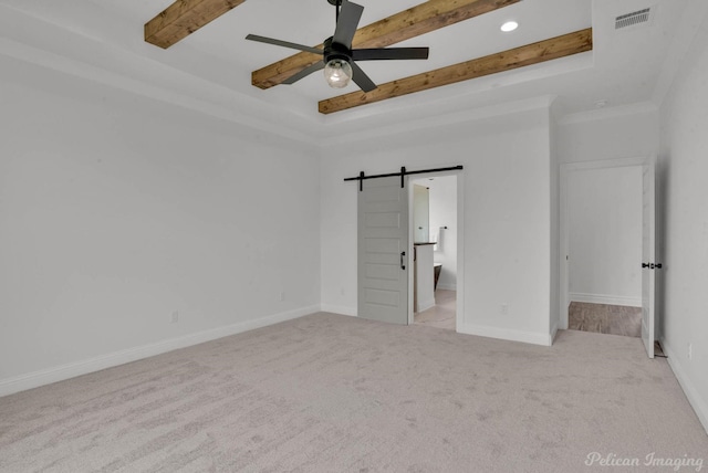 unfurnished bedroom with visible vents, beam ceiling, a barn door, baseboards, and carpet flooring