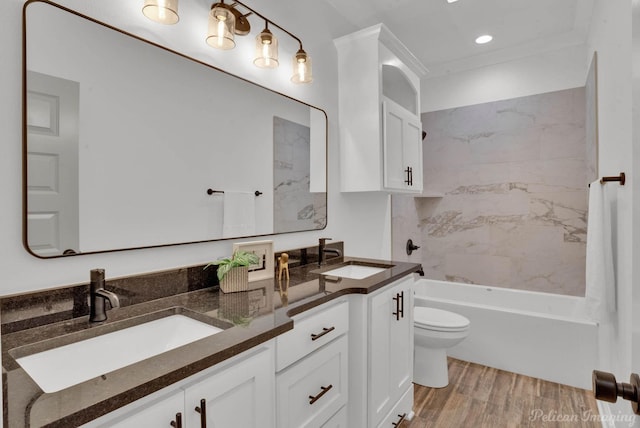 bathroom featuring double vanity, toilet, a sink, and wood finished floors