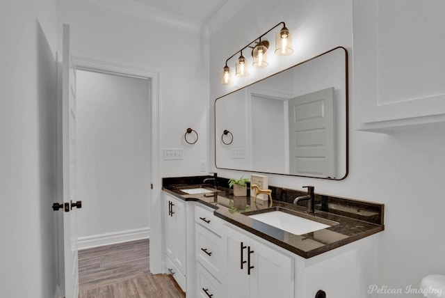 bathroom featuring a sink, baseboards, double vanity, and wood finished floors