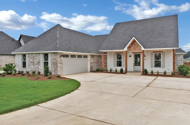 view of front of property with roof with shingles, an attached garage, concrete driveway, and a front lawn