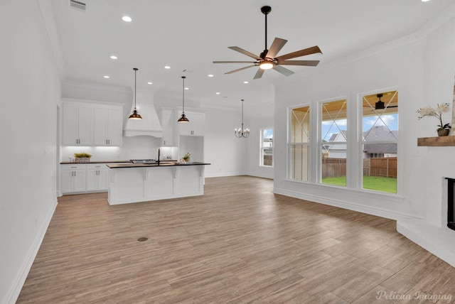 kitchen with ornamental molding, light wood finished floors, open floor plan, and dark countertops