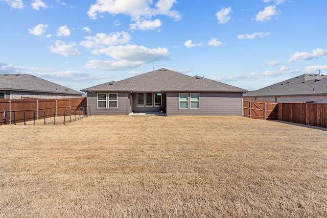 rear view of property with a fenced backyard and a lawn