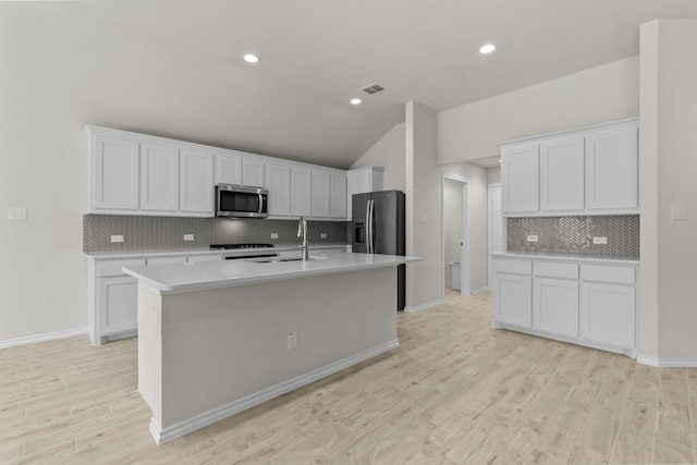 kitchen with light wood-style flooring, visible vents, light countertops, appliances with stainless steel finishes, and an island with sink