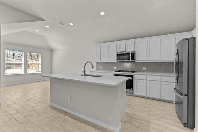 kitchen featuring decorative backsplash, vaulted ceiling, stainless steel appliances, light countertops, and a sink