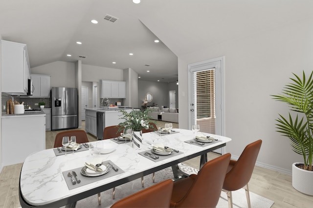 dining space with light wood finished floors, baseboards, visible vents, vaulted ceiling, and recessed lighting