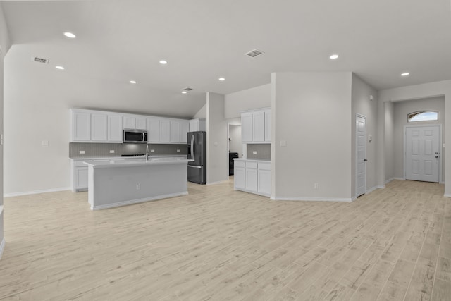 kitchen with visible vents, stainless steel microwave, open floor plan, and black fridge