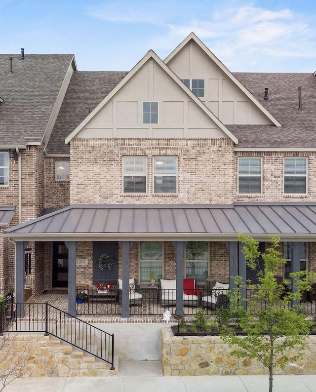 view of property with a standing seam roof, roof with shingles, and brick siding