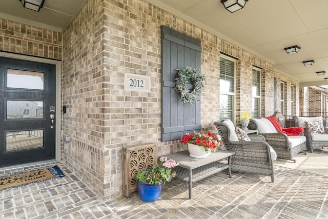 entrance to property featuring covered porch and brick siding