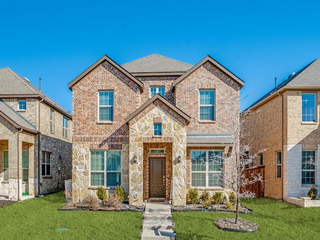 view of front of property with stone siding, brick siding, a front lawn, and roof with shingles