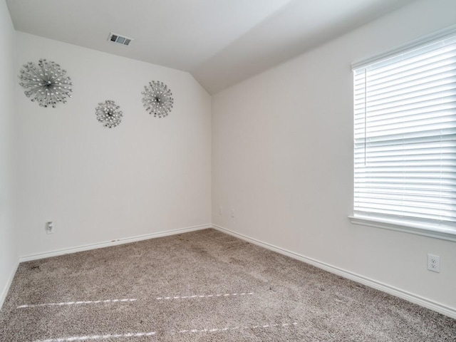 unfurnished room featuring carpet floors, baseboards, visible vents, and vaulted ceiling