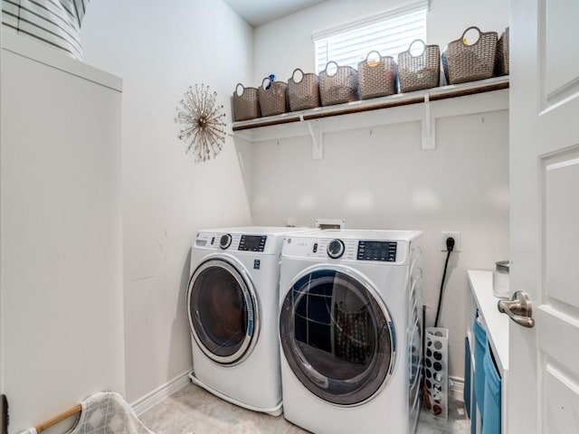 clothes washing area with laundry area, baseboards, and washing machine and clothes dryer