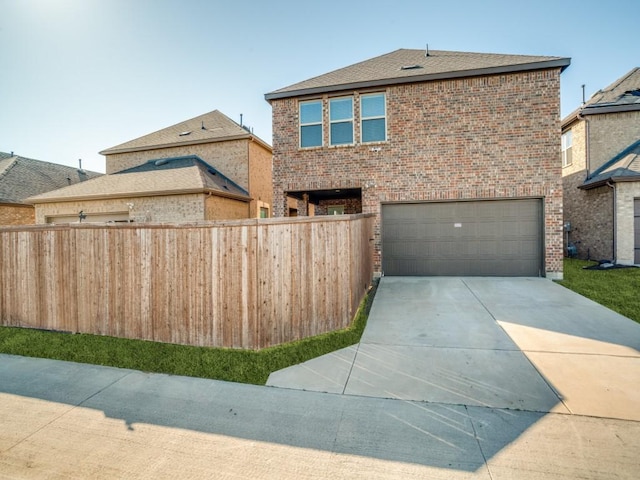 traditional-style home with concrete driveway, brick siding, an attached garage, and fence