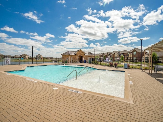 community pool with a residential view, fence, and a patio