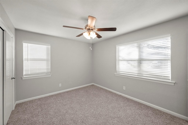 empty room with ceiling fan, carpet floors, and baseboards