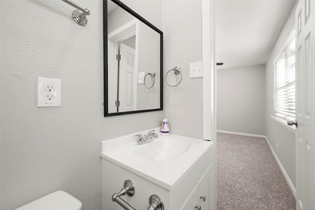 half bathroom with baseboards, vanity, and toilet