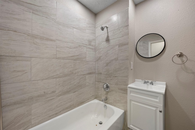 bathroom with shower / bathtub combination, a textured wall, and vanity