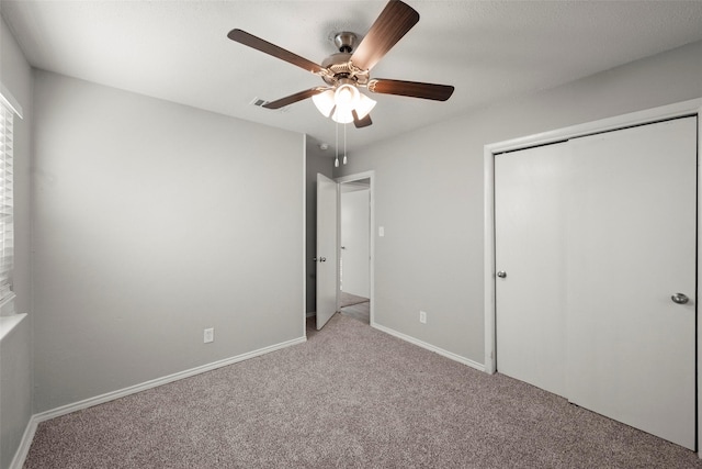 unfurnished bedroom with baseboards, visible vents, a ceiling fan, carpet floors, and a closet