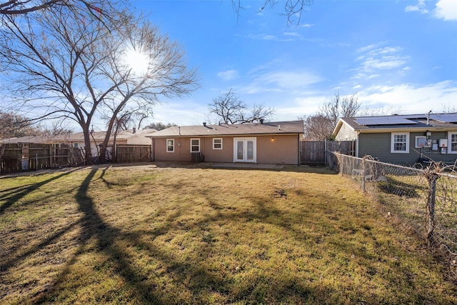 back of property featuring french doors, a fenced backyard, and a lawn