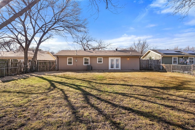 rear view of property featuring french doors, a lawn, central AC unit, and a fenced backyard