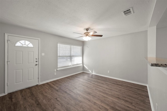 foyer entrance featuring dark wood-style floors, baseboards, visible vents, and a textured ceiling