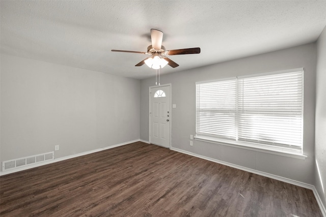 foyer with dark wood-style flooring, visible vents, a textured ceiling, and baseboards