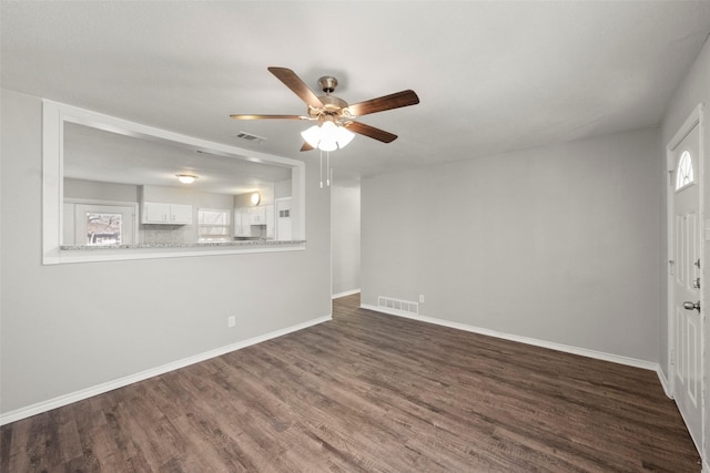 unfurnished living room featuring ceiling fan, dark wood-type flooring, visible vents, and baseboards