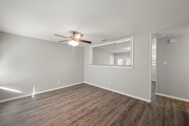 empty room featuring a textured ceiling, dark wood finished floors, visible vents, and baseboards