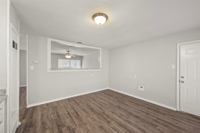 spare room with visible vents, baseboards, dark wood finished floors, and a textured ceiling