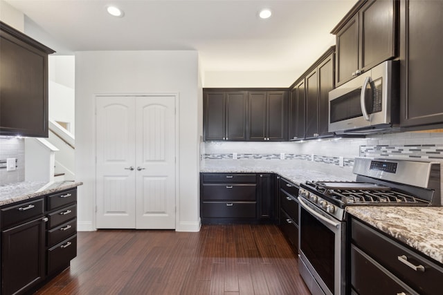 kitchen with stainless steel appliances, dark brown cabinets, light stone counters, and dark wood-style floors