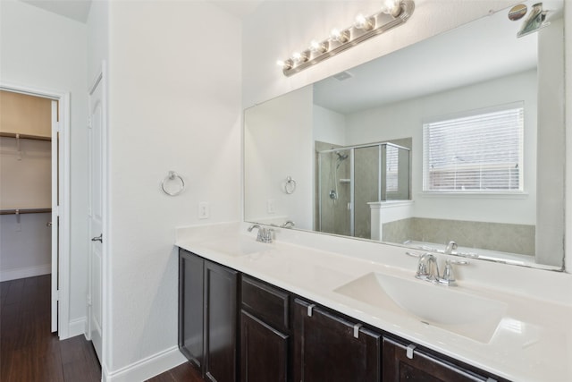 bathroom with double vanity, wood finished floors, a stall shower, and a sink