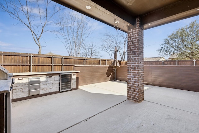 view of patio with a fenced backyard, beverage cooler, and area for grilling