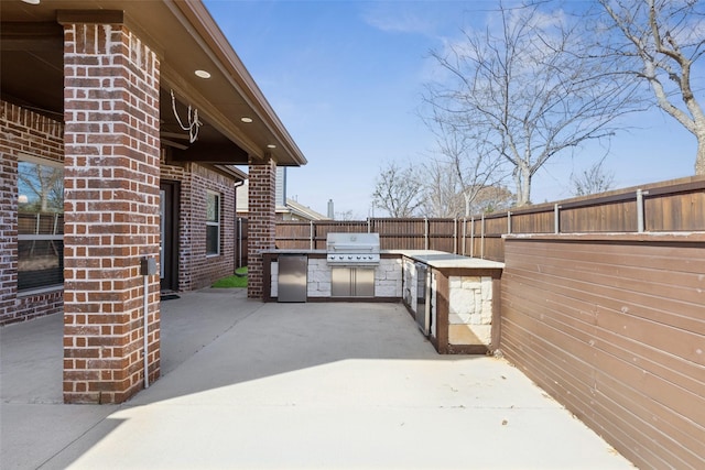 view of patio with a fenced backyard, a grill, and an outdoor kitchen