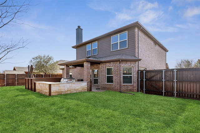 rear view of property with a fenced backyard, brick siding, area for grilling, a lawn, and a chimney